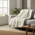 Ultra soft cream white faux fur throw blanket draped over a sofa